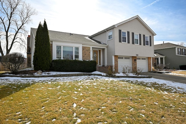 split level home with a garage, a lawn, brick siding, and driveway