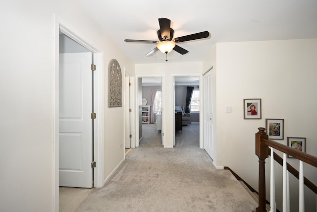 hallway with baseboards, light carpet, and an upstairs landing