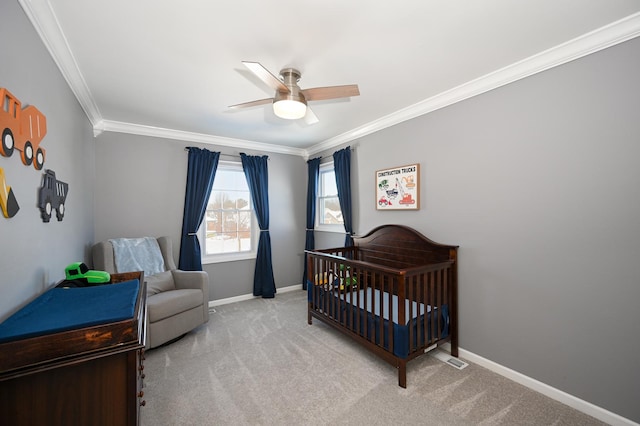 carpeted bedroom with a crib, crown molding, a ceiling fan, and baseboards