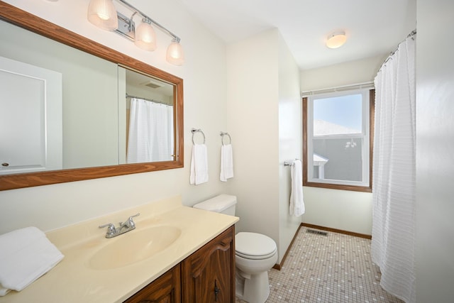 bathroom featuring vanity, baseboards, visible vents, tile patterned floors, and toilet