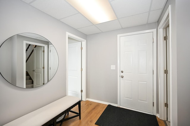 entryway featuring stairway, a paneled ceiling, light wood-type flooring, and baseboards