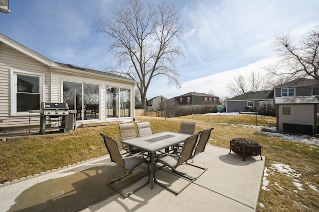 view of patio featuring fence, a grill, outdoor dining space, and an outdoor fire pit