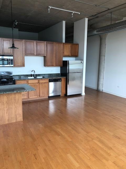 kitchen featuring decorative light fixtures, wood finished floors, appliances with stainless steel finishes, and a sink