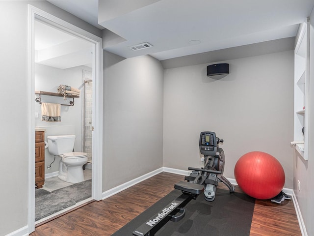 exercise area with visible vents, baseboards, and wood finished floors