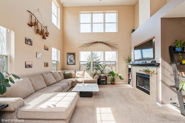 living room with a fireplace, baseboards, carpet, and a towering ceiling