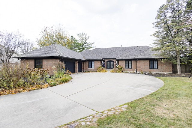 view of front facade with a garage, a front yard, brick siding, and driveway