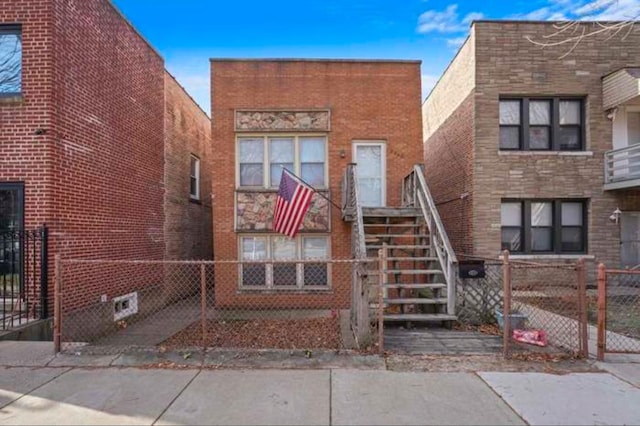 view of front of house with brick siding, fence, and stairway