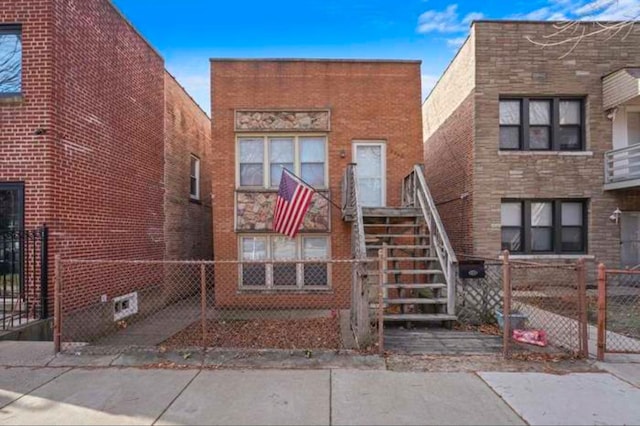 view of front of house with stairs, fence, and brick siding