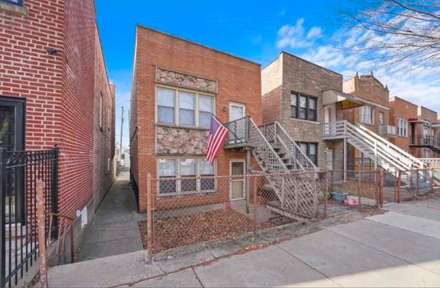 view of front of house with stairway, fence, and brick siding