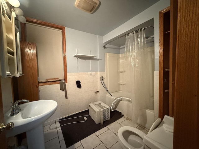 full bathroom featuring shower / tub combo, tile walls, toilet, tile patterned floors, and wainscoting