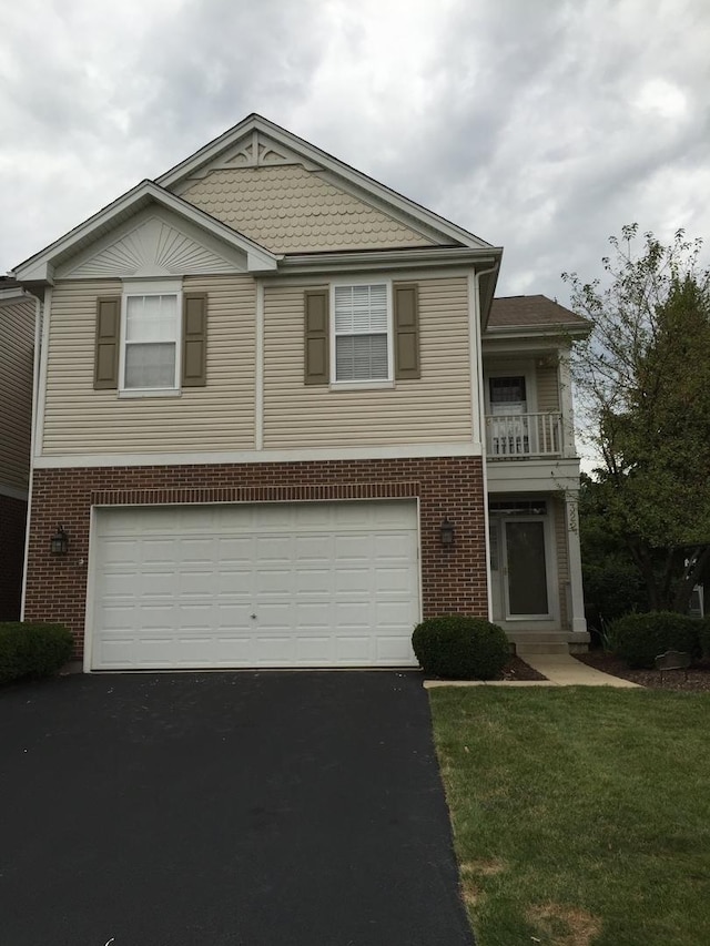 view of front of house featuring brick siding, a front lawn, aphalt driveway, a garage, and a balcony