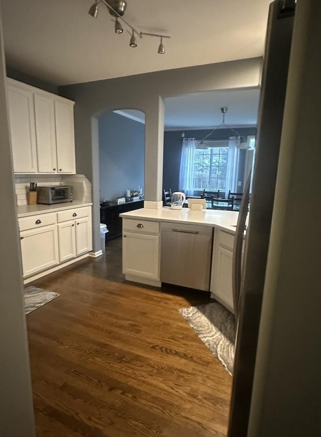 kitchen with arched walkways, dark wood finished floors, white cabinets, and light countertops