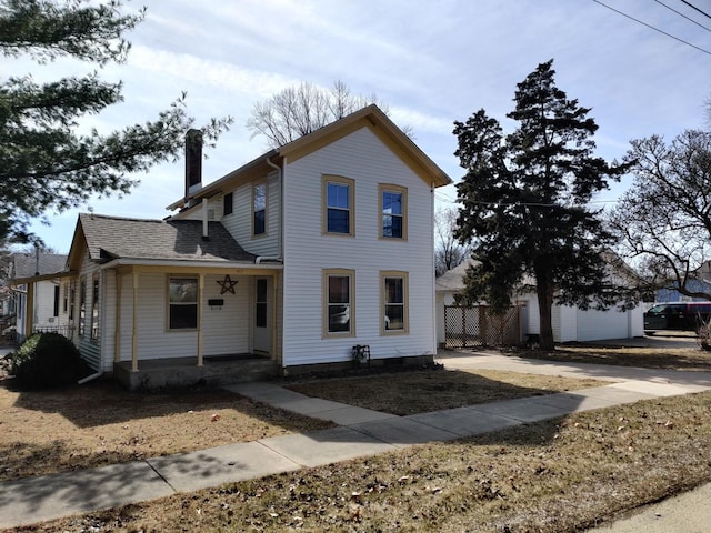 traditional-style home featuring a porch, a chimney, roof with shingles, and fence