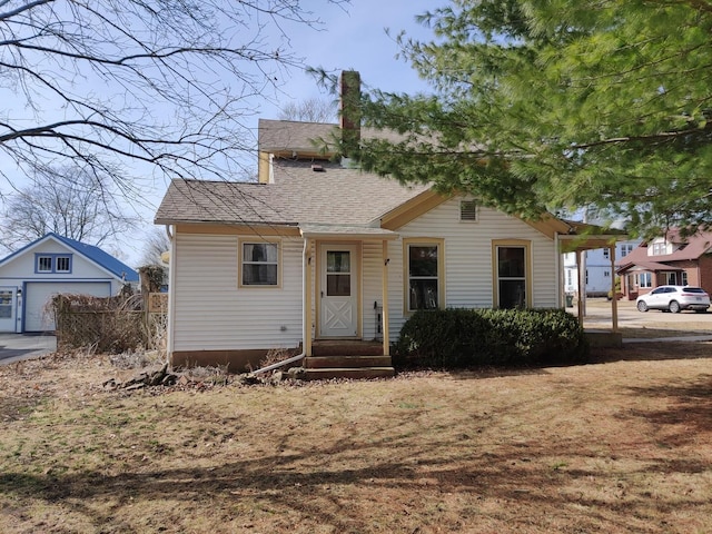 view of front facade featuring roof with shingles and a chimney