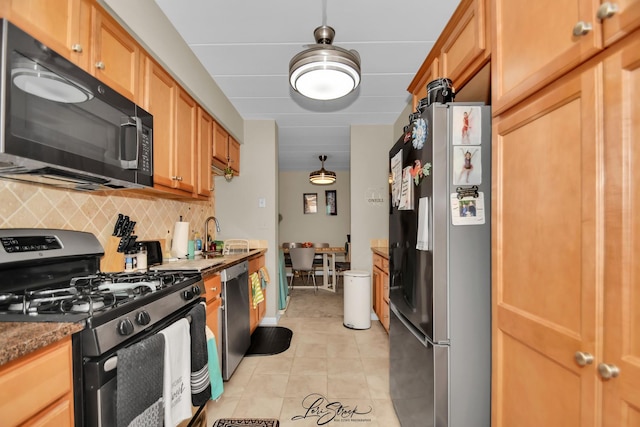 kitchen with brown cabinets, a sink, backsplash, stainless steel appliances, and light tile patterned floors