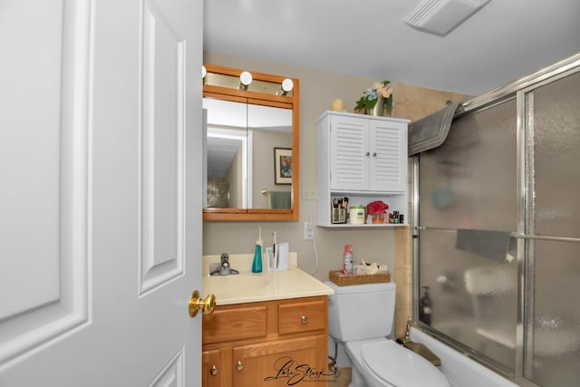 bathroom with vanity, toilet, visible vents, and shower / bath combination with glass door