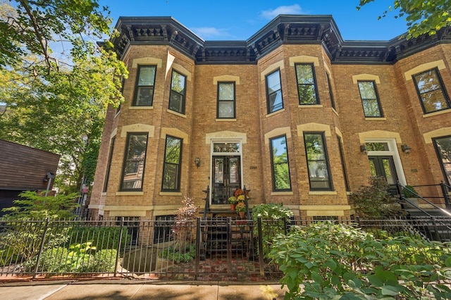 multi unit property with french doors, brick siding, and a fenced front yard