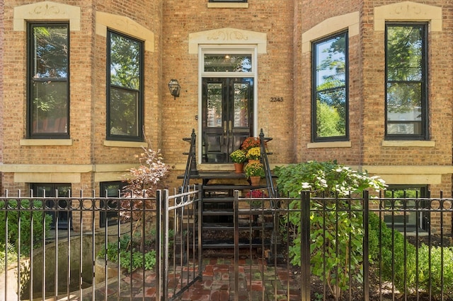 entrance to property featuring brick siding and fence