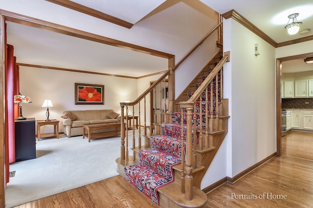 stairway with crown molding, wood finished floors, and baseboards