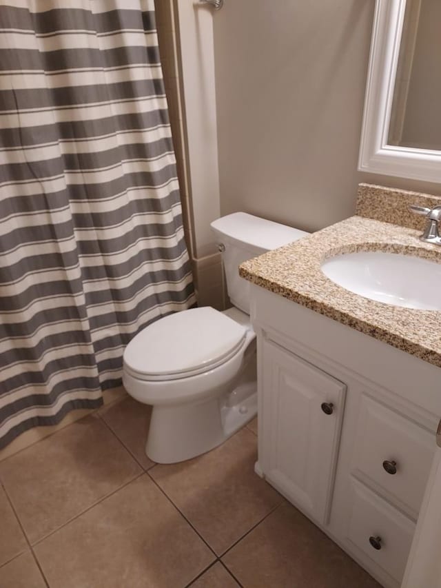 bathroom with toilet, vanity, and tile patterned flooring