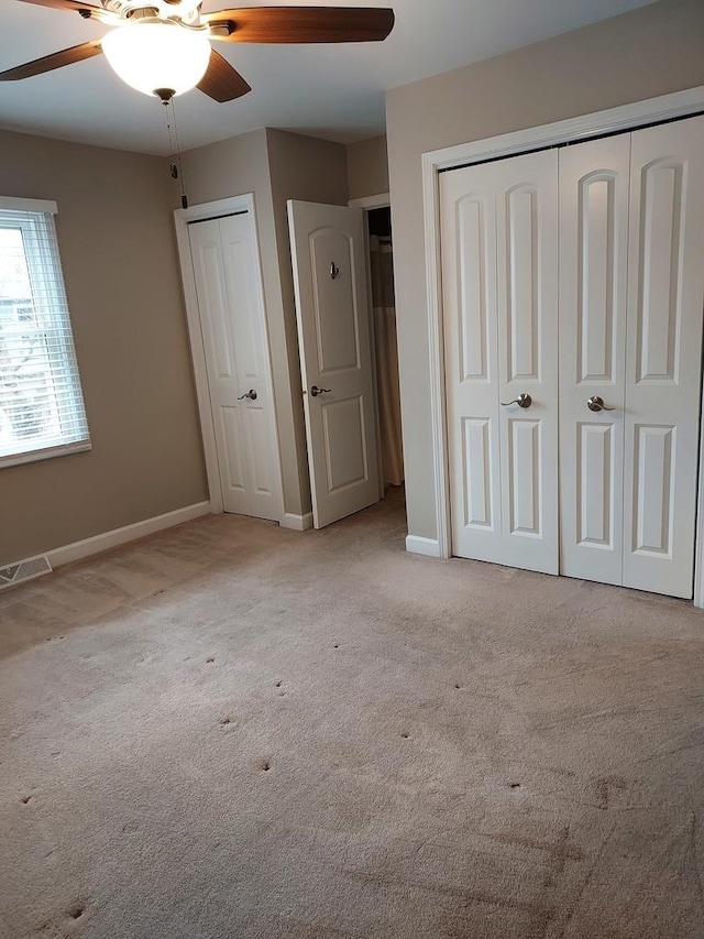 unfurnished bedroom with visible vents, baseboards, multiple closets, and carpet flooring