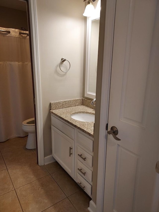 bathroom with toilet, vanity, and tile patterned flooring