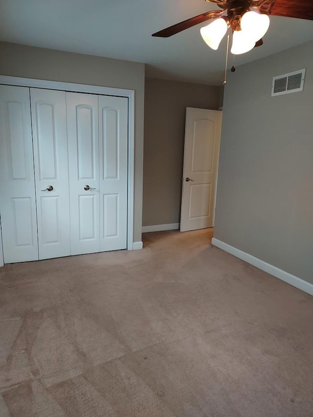 unfurnished bedroom featuring visible vents, light carpet, a ceiling fan, a closet, and baseboards