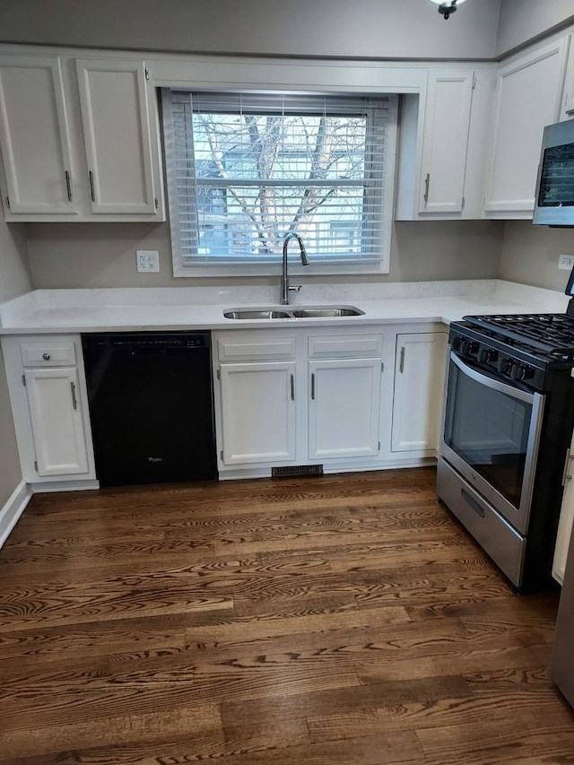 kitchen featuring dark wood finished floors, appliances with stainless steel finishes, white cabinetry, and a sink