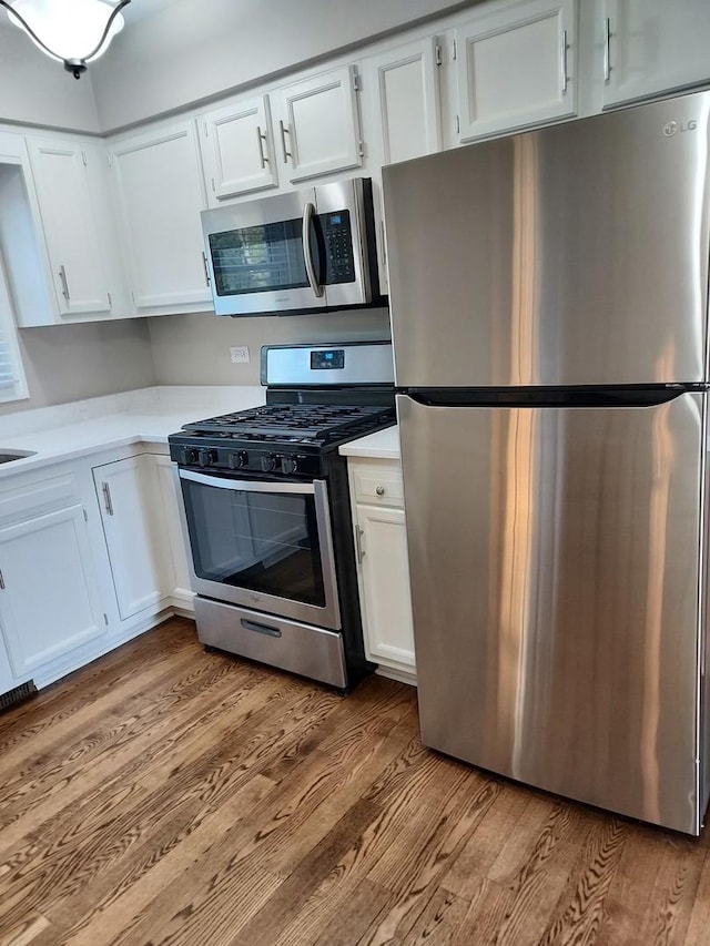 kitchen featuring appliances with stainless steel finishes, wood finished floors, and white cabinets