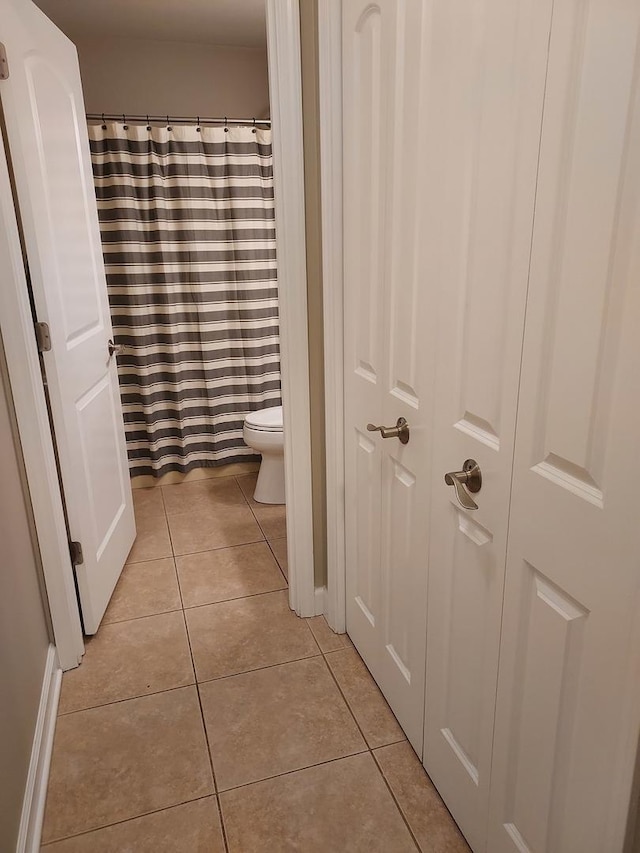 bathroom featuring tile patterned flooring, toilet, and a shower with curtain