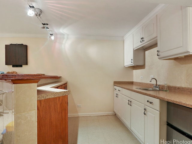 kitchen featuring a sink, crown molding, white cabinets, baseboards, and light countertops