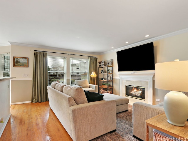 living room featuring ornamental molding, a tile fireplace, wood finished floors, baseboards, and recessed lighting