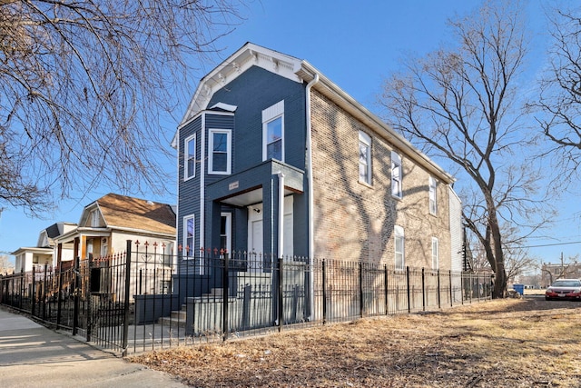 view of side of home featuring brick siding and a fenced front yard