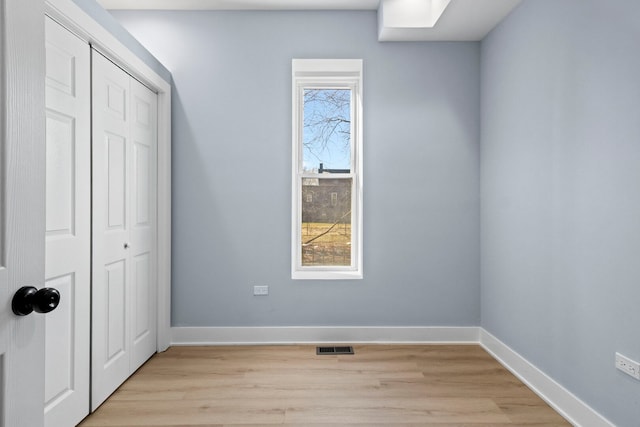 unfurnished bedroom featuring a closet, visible vents, light wood-type flooring, and baseboards