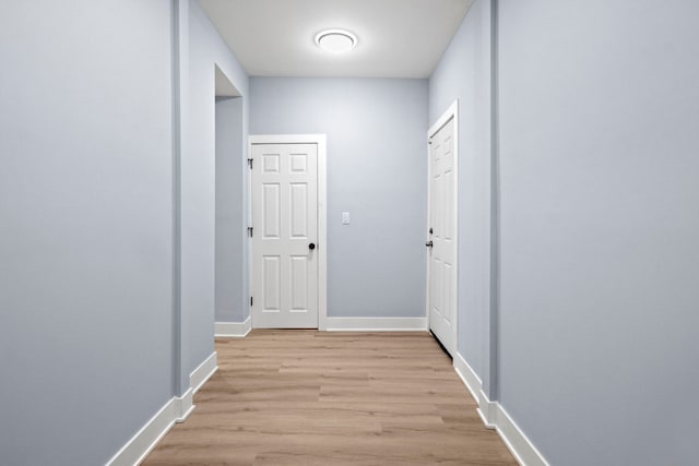 corridor featuring light wood-type flooring and baseboards