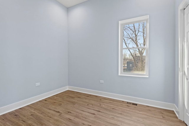 empty room featuring light wood finished floors, visible vents, and baseboards