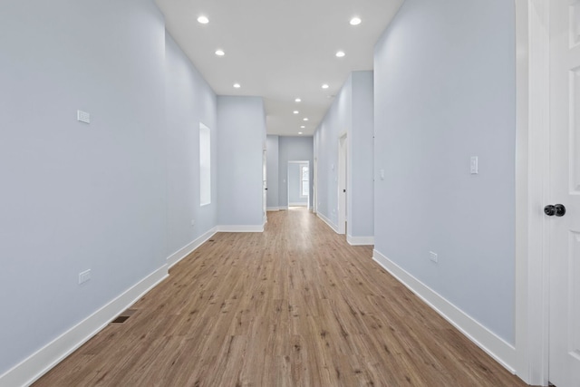 corridor with light wood-style floors, recessed lighting, and baseboards