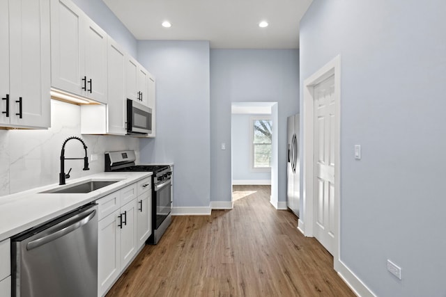 kitchen featuring tasteful backsplash, white cabinetry, stainless steel appliances, and a sink