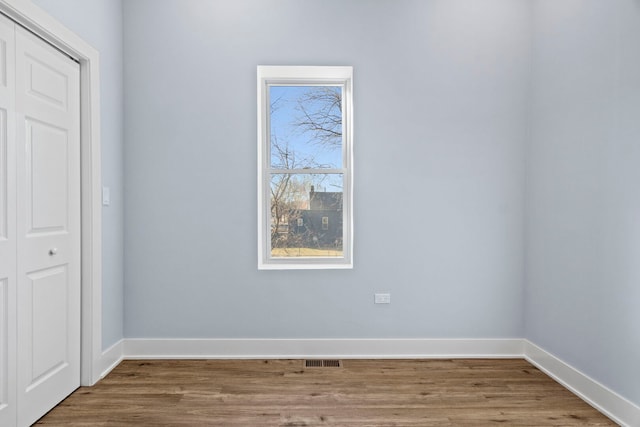 unfurnished bedroom with a closet, baseboards, visible vents, and wood finished floors