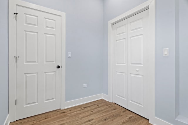 unfurnished bedroom featuring a closet, light wood-type flooring, and baseboards