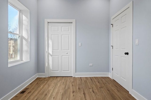 unfurnished bedroom with visible vents, baseboards, and wood finished floors