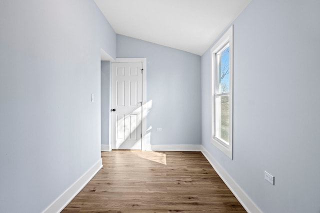 unfurnished room with wood finished floors, baseboards, and vaulted ceiling