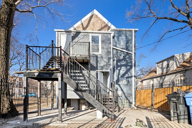 back of house featuring stairway and fence