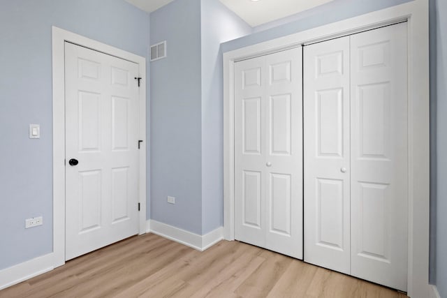 unfurnished bedroom with visible vents, baseboards, light wood-style floors, and a closet