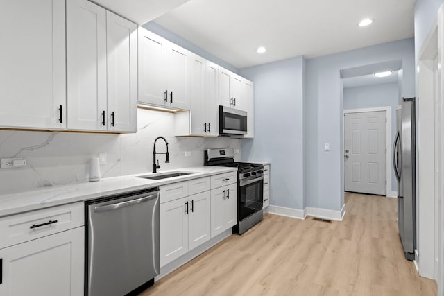 kitchen with white cabinetry, stainless steel appliances, light wood-type flooring, and a sink