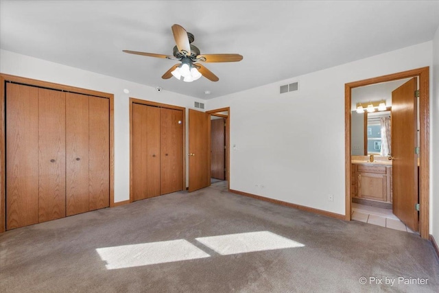 unfurnished bedroom with visible vents, two closets, baseboards, and carpet floors