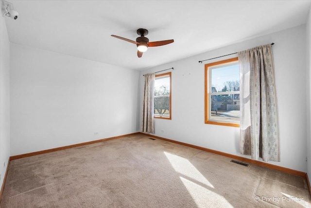 unfurnished room with light carpet, baseboards, visible vents, and ceiling fan