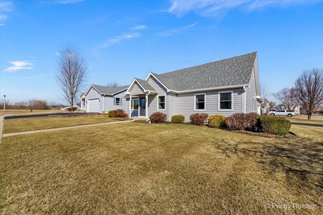 ranch-style home featuring an attached garage, driveway, a shingled roof, and a front yard