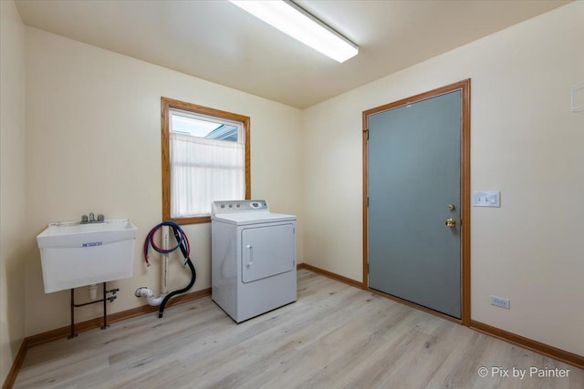 clothes washing area with light wood finished floors, baseboards, laundry area, washer / dryer, and a sink