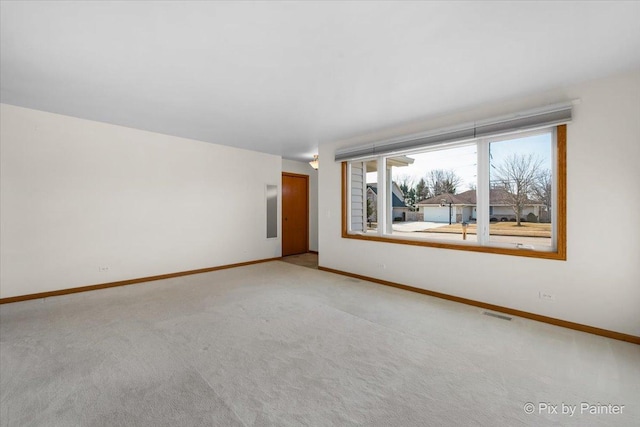 spare room with baseboards, visible vents, and light carpet